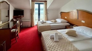 Ein Hotelzimmer mit zwei Betten, einem Schreibtisch, einem Fernseher und einem großen Fenster.