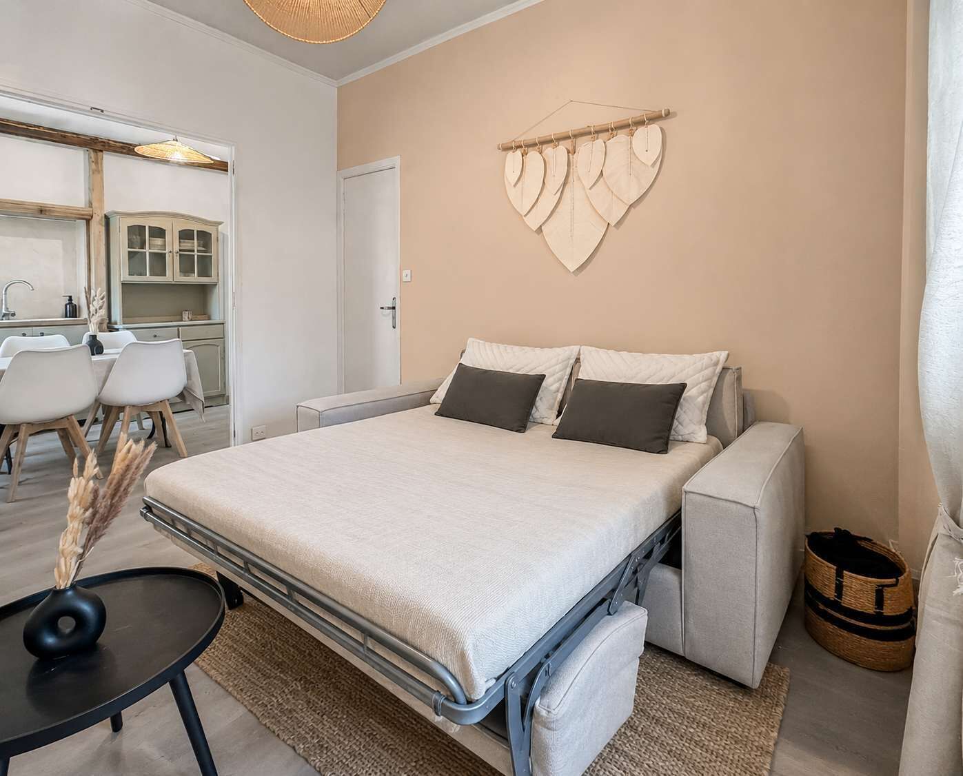 Een kleine slaapkamer met een bed, nachtkastjes, een wandplank en uitzicht op de aangrenzende keuken.