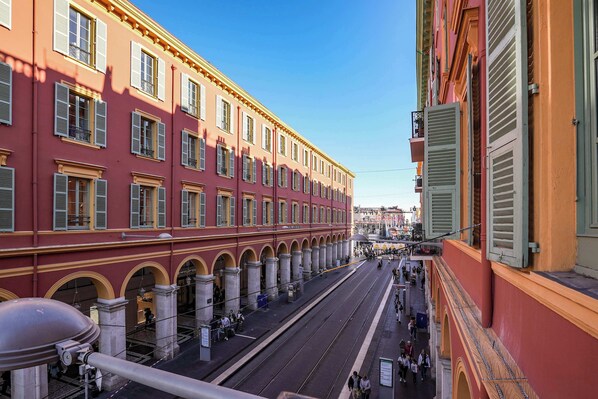 A street with buildings, a tram, and pedestrians. - Massena Infinity (Nice)