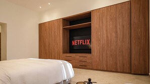 A bedroom with a bed, wooden wardrobe, and a TV screen displaying 'NETFLIX'.