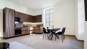 A modern kitchen with wood paneling, a dining area with a table and chairs, and a large window providing natural light.