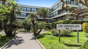 A sign for 'LES CARAVELLES' indicating a building with a modern architectural style, surrounded by lush greenery and palm trees. - Le Cap Vert - 4 pers, terrasse & piscine (Mandelieu-la-Napoule)