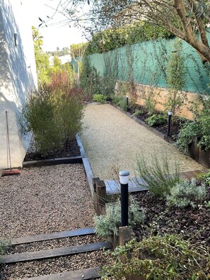 A garden area with gravel paths, wooden borders, and various plants.