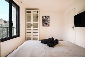 A bedroom with a bed, a wardrobe, a painting, and a TV.