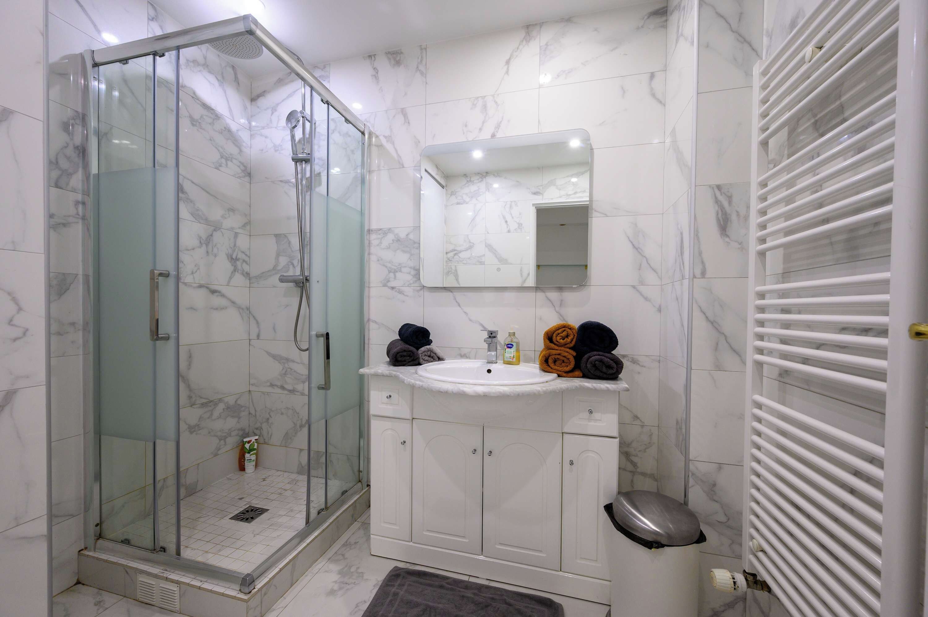 A bathroom with a glass-enclosed shower, a white sink, and a mirror above it.