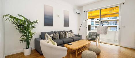 A modern living room with a grey sofa, a coffee table, and a potted plant.