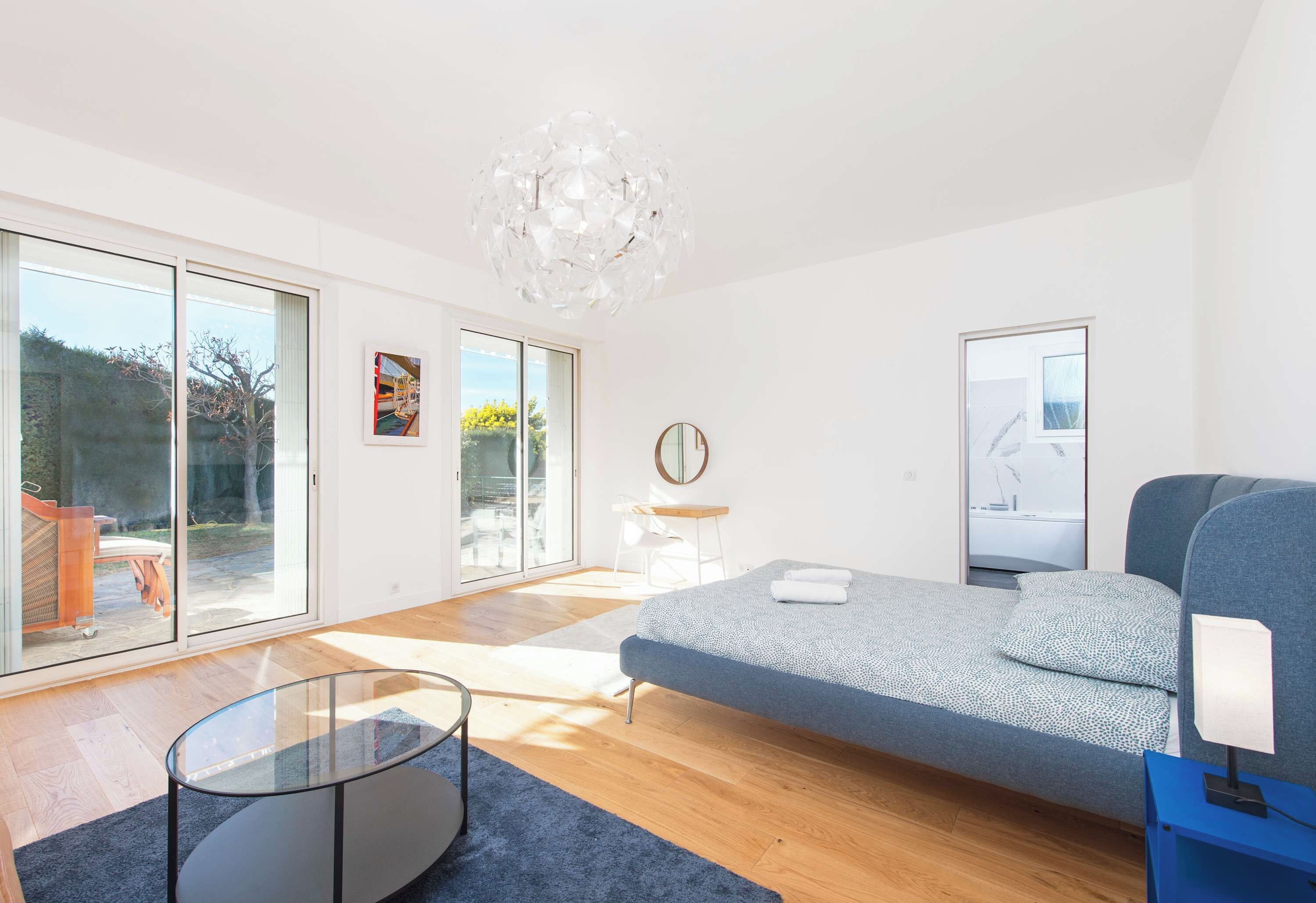 A modern living room with a sofa, a glass coffee table, and a chandelier.