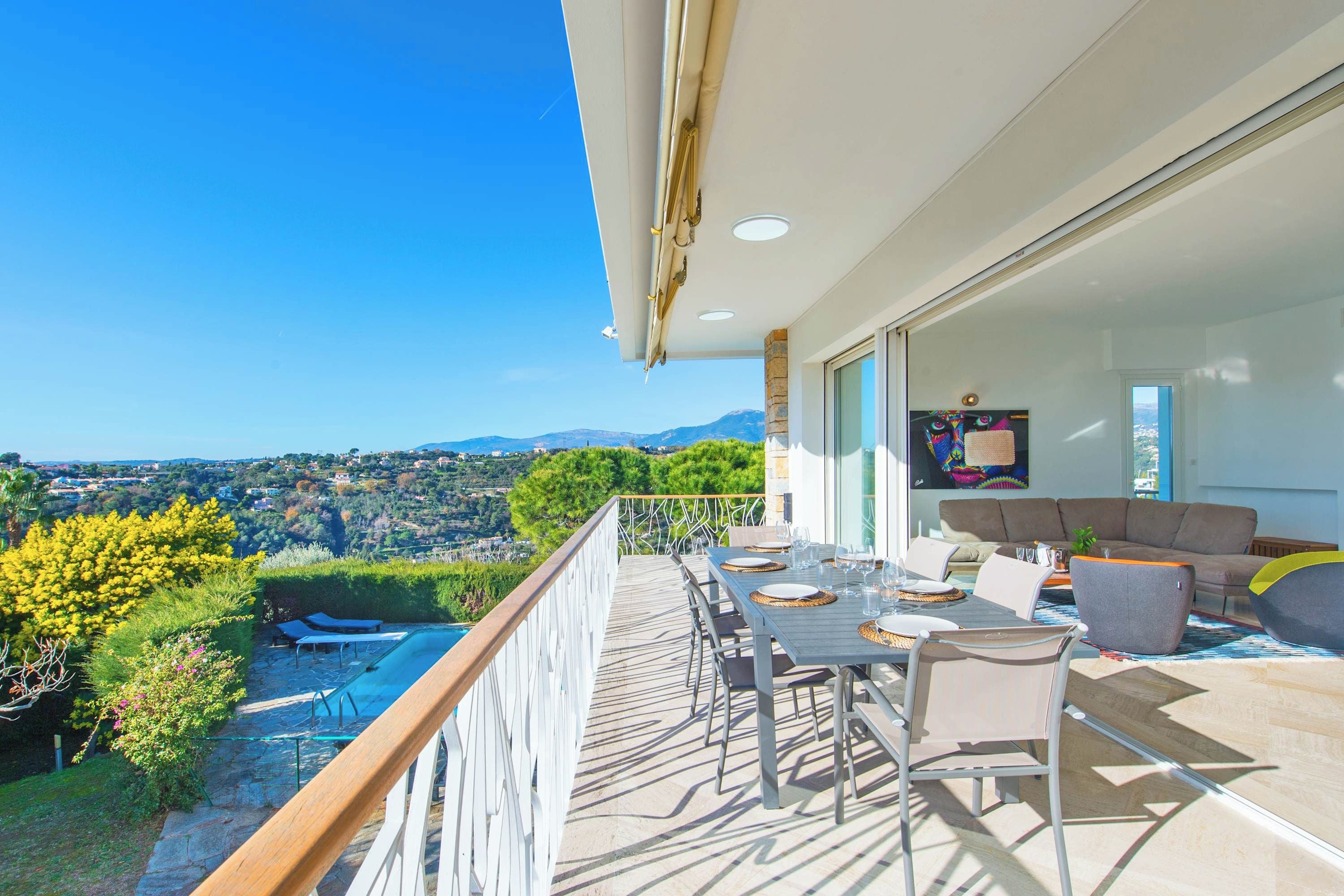 A balcony with a dining set, a sofa, and a TV.