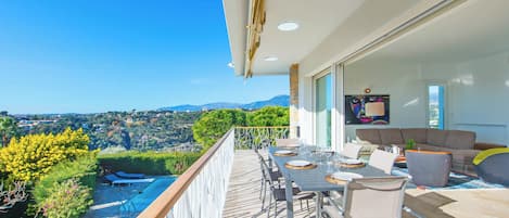 A balcony with a dining set, a sofa, and a TV.