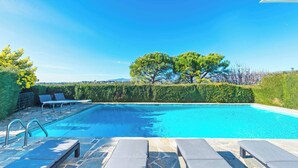 A swimming pool with lounge chairs and a clear sky.