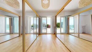 A spacious room with large sliding glass doors leading to a balcony, wooden flooring, and a modern ceiling design.