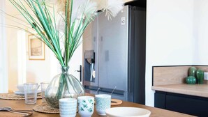 A dining table with a vase of dried plants, clear glassware, and a white bowl.