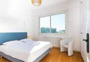 A bedroom with a bed, a chair, a window, and a door.