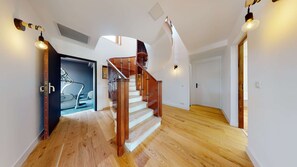 Una escalera con barandillas de madera y balaustrada de cristal que lleva a una plataforma.