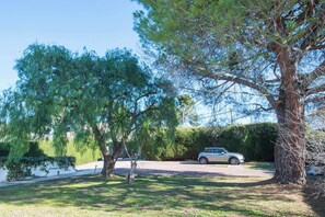 A residential driveway with a parked car, surrounded by mature trees and a well-maintained lawn.