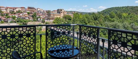 Ein Balkon mit Tisch und Stühlen, mit Blick auf eine Stadt mit Gebäuden und einer Brücke.