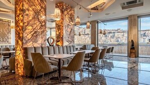 Un restaurante moderno con columnas de mármol, asientos de cuero y amplias ventanas con vistas a la ciudad.