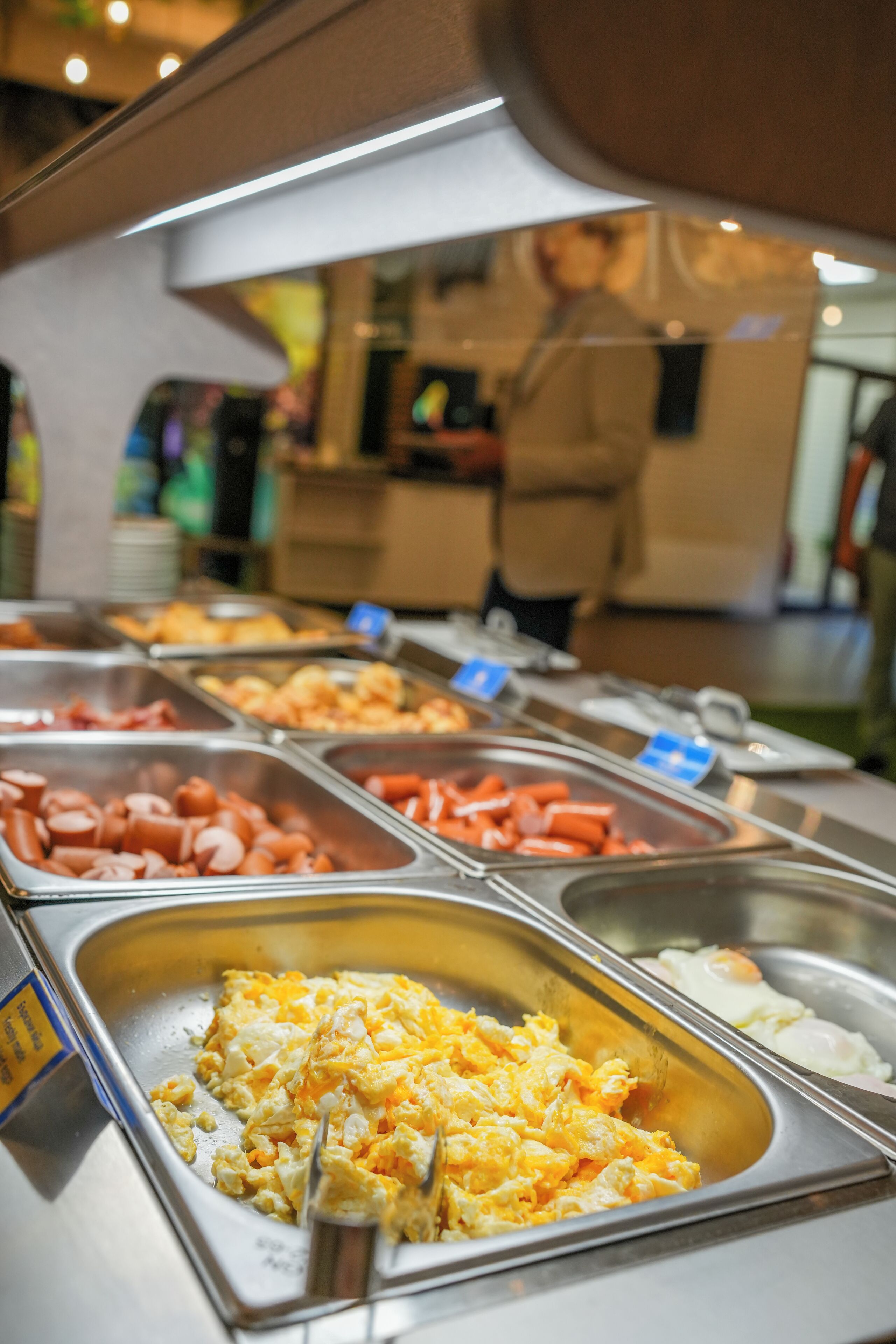 Un bufé con diversas opciones de comida, como huevos revueltos, salchichas y otros platos.