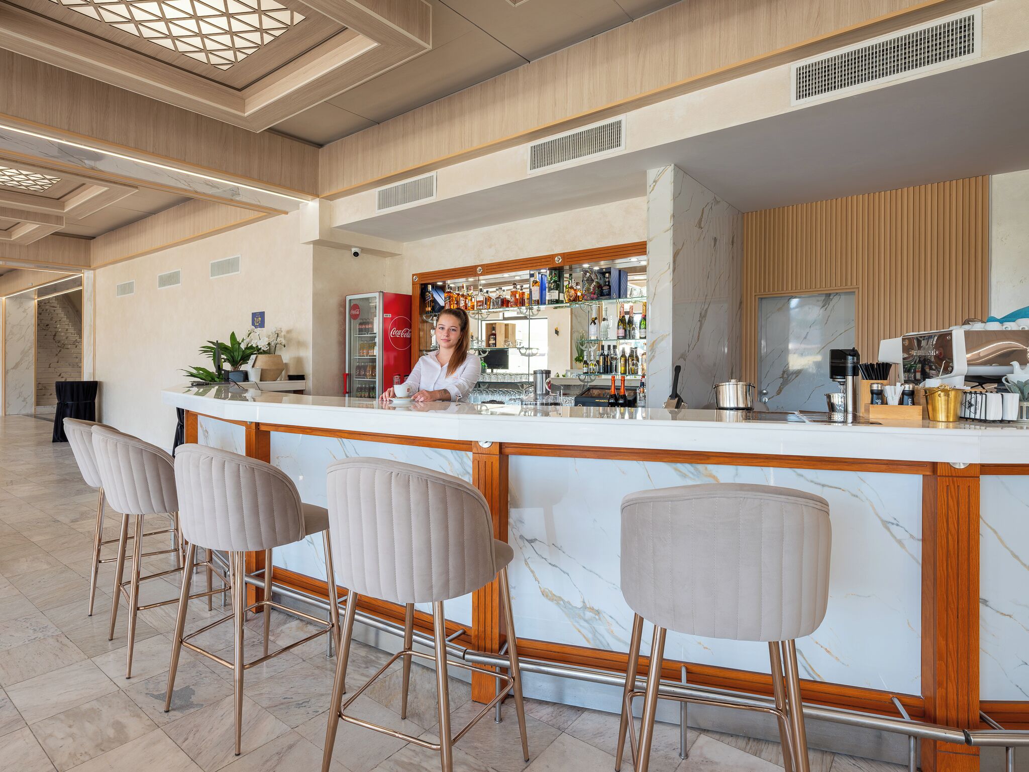 Een bar met een marmeren aanrecht, barkrukken en een drankdispenser.