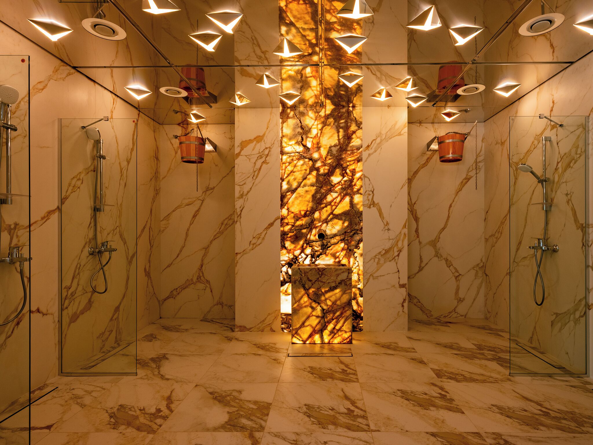 Een luxe badkamer met marmeren wanden, een centrale kolom en meerdere douches.
