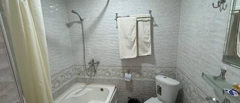Une salle de bain équipée d’une baignoire, de toilettes, d’un lavabo et d’une douche.