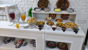 Monipuolinen buffet, jossa on tarjolla erilaisia ruokia ja juomia, kuten hedelmiä, leivonnaisia ja kastikkeita.