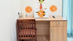 Ein Zimmer mit einem Holztisch, einem Stuhl, einer kleinen Kommode und einer Wand mit orangefarbenen Blumendekorationen.