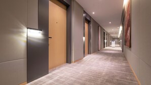 A modern hotel corridor with a carpeted floor, recessed lighting, and doors on both sides. - World Hotel Qingxian County Cangzhou (Cangzhou)