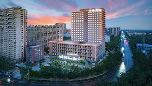 A modern hotel with a prominent central building, surrounded by high-rise residential buildings, and a busy road with vehicles. - World Hotel Qingxian County Cangzhou (Cangzhou)