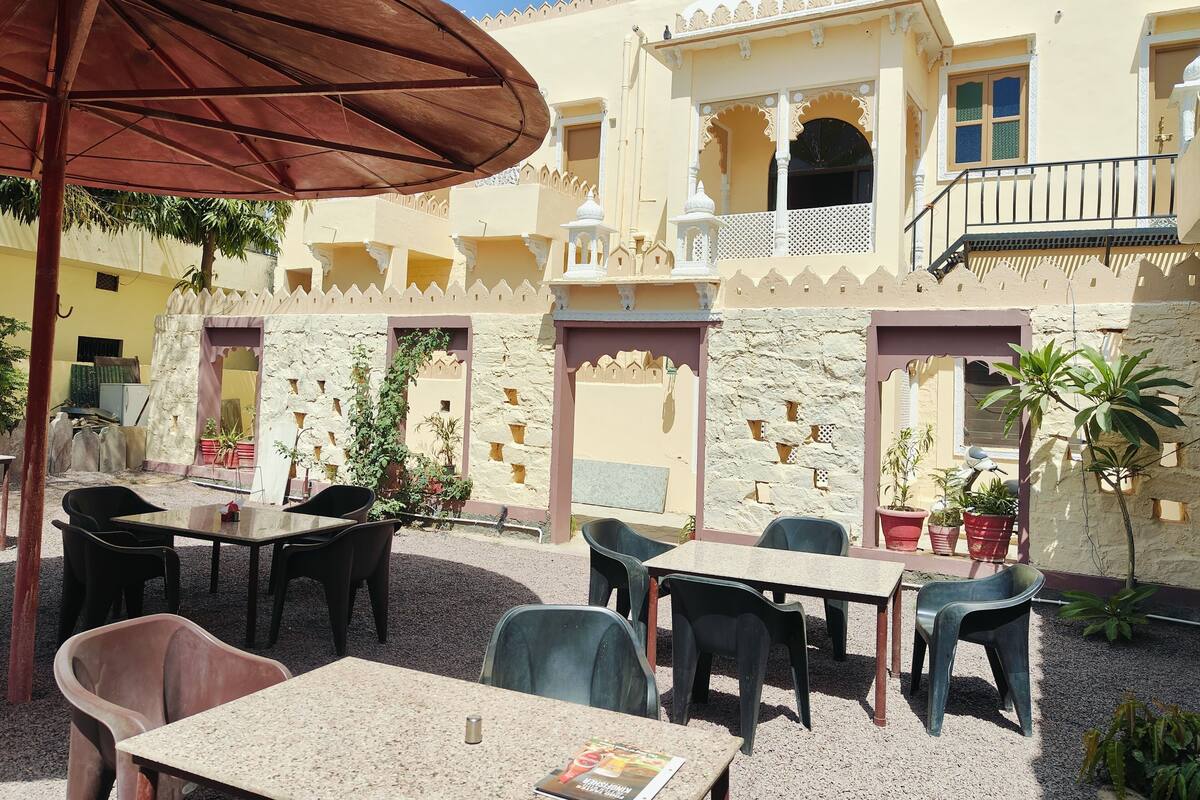 An outdoor seating area with tables and chairs, surrounded by a building with traditional architecture.