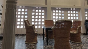 Una habitación con piso estampado, sillas de mimbre y un candelabro.