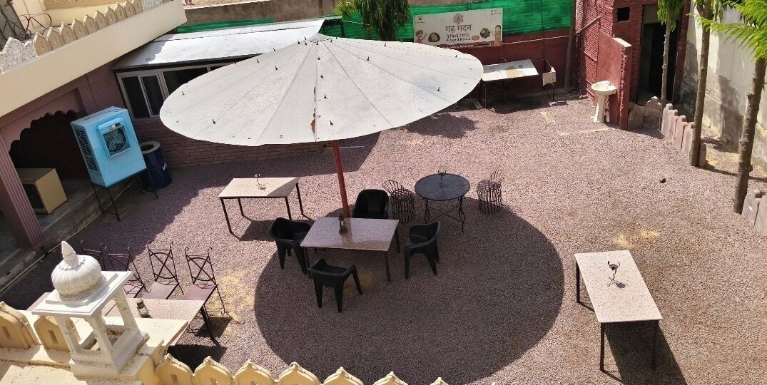 An outdoor seating area with tables and chairs, a large umbrella, and a water dispenser.