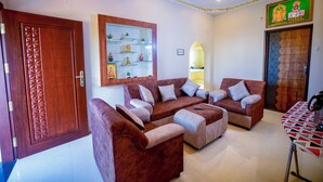 A living room with a sofa set, a wooden door, a framed picture, and a small table. - SES LINGA COTTAGE (Palayankottai)