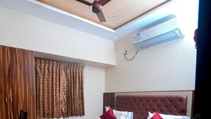 A bedroom with a bed, a ceiling fan, an air conditioning unit, a wooden desk, and a chair. - SES LINGA COTTAGE (Palayankottai)