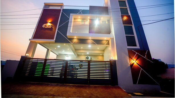 A modern building with a glass facade, multiple levels, and a gated entrance. - SES LINGA COTTAGE (Palayankottai)