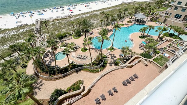 Un resort con un amplio espacio de piscina, una playa y vistas al océano.
