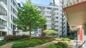 A modern apartment building with balconies, a central tree, and a small garden area. - 2br on Tjuvholmen with sea view (Oslo)