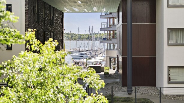A modern building with a covered outdoor area overlooking a marina with boats. - 2br on Tjuvholmen with sea view (Oslo)