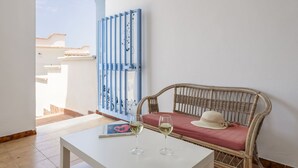 A room with a wicker sofa, a white table, and a blue gate. - Nice apartment for 6 people with A/C, WIFI, TV and terrace (Balestrate-foce)