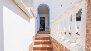 A staircase leading to a doorway with a blue archway, white balustrades, and a brick wall. - Nice apartment for 6 people with A/C, WIFI, TV and terrace (Balestrate-foce)