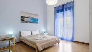 Een slaapkamer met een bed, nachtkastjes, een lamp, een schilderij en een raam met gordijnen.