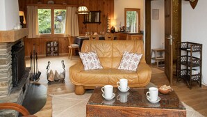 A cozy living room with a leather sofa, a fireplace, and a dining area with wooden furniture. - Stunning private villa for 6 guests with WIFI, TV and terrace (Les Vérines (chamoson))