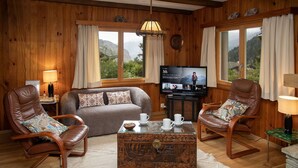 A cozy living room with wooden walls, a sofa, two leather chairs, a coffee table, and a TV. - Stunning private villa for 6 guests with WIFI, TV and terrace (Les Vérines (chamoson))