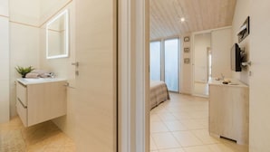 A modern bathroom with a large mirror, a sink, and a towel rack.