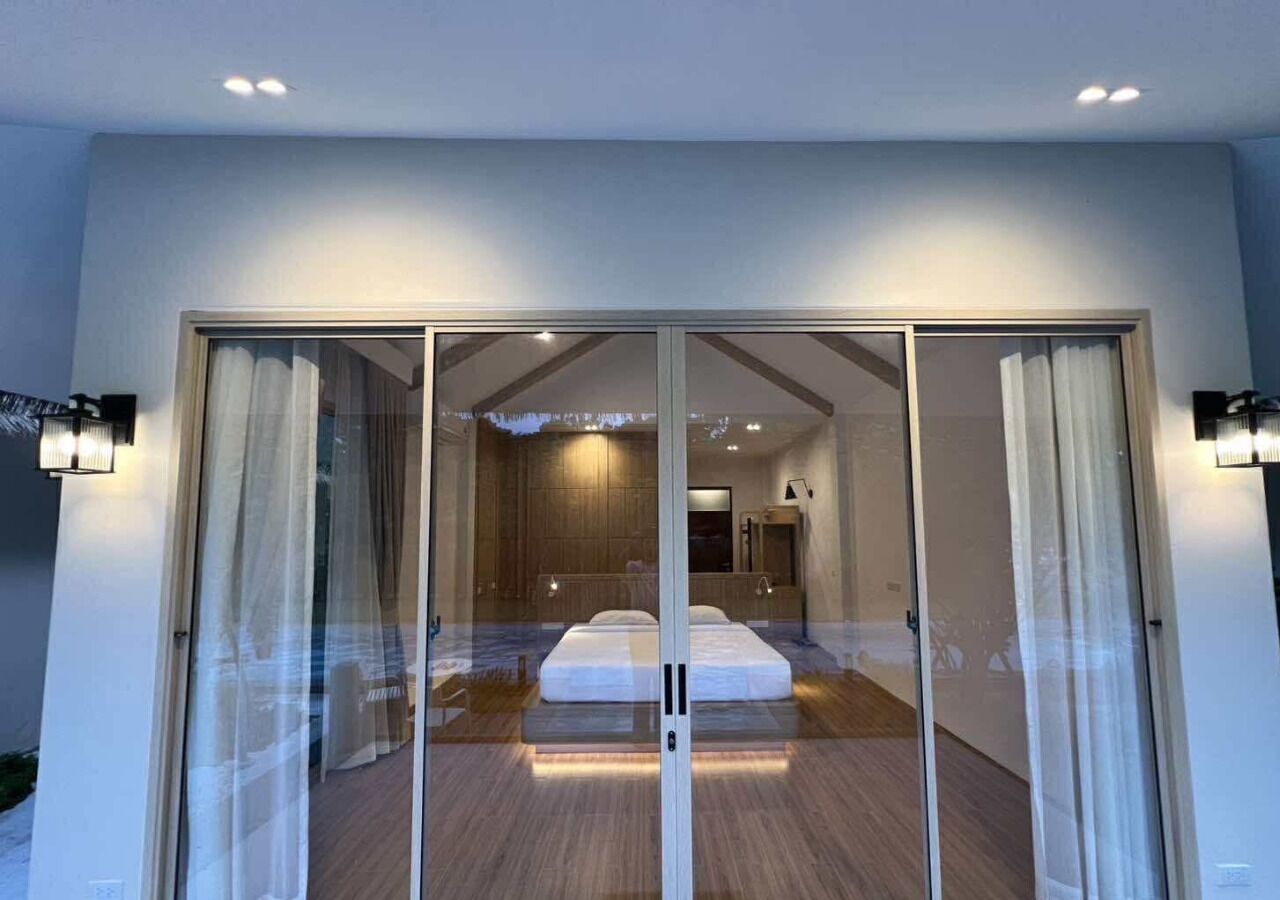 Ein modernes Schlafzimmer mit einem großen Bett, Schiebegläsern und Blick auf den Nachthimmel.