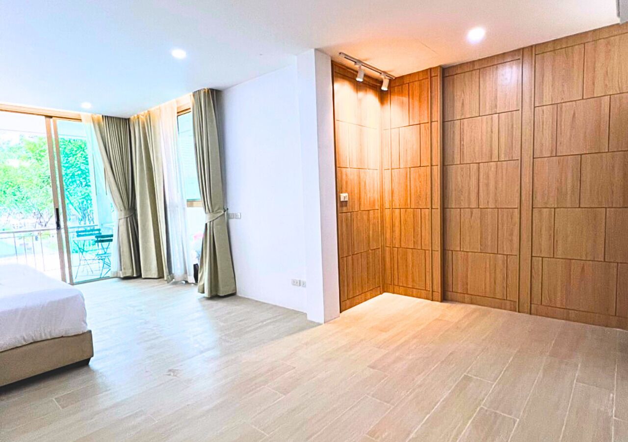 Un dormitorio moderno con una cama grande, un armario de madera y un ventanal corredero que da a un balcón.