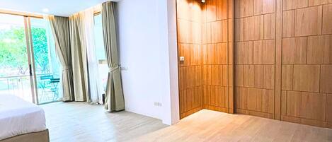 Un dormitorio moderno con una cama grande, un armario de madera y un ventanal corredero que da a un balcón.