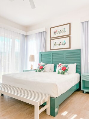 Un dormitorio ordenado con cama, mesita de noche, lámpara y cuadros en la pared.