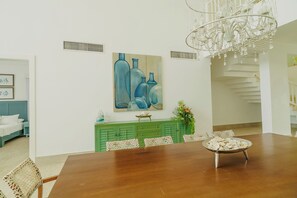 A dining area with a wooden table, chairs, a chandelier, a green cabinet, and a painting on the wall. - 4 Bedroom Luxury Villa Peninsula Esmeralda Luxury Hotel & Villas (Cofresi)