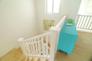 Eine Treppe mit weißer Handlauf führt zu einem Raum mit blauer Akzentwand und einem Fenster.